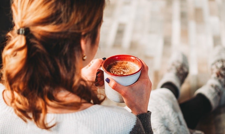 Schreibblockade Beitragsbild Kaffeepause: Rückansicht einer jungen Frau mit Kaffeetasse